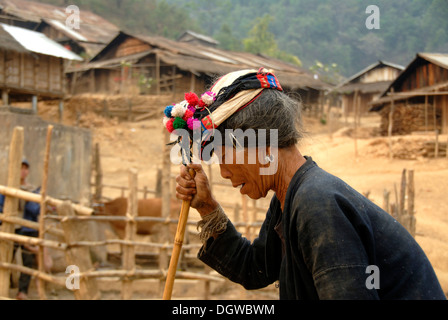 De la vieille femme Phoussang groupe ethnique s'appuyant sur un bâton et de la marche dans une intuition vers le bas chemin portant un chapeau pompon coloré Banque D'Images