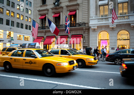 Le trafic à la brunante, Cartier et boutiques Versace à l'arrière, les taxis jaunes, taxis, 5e Avenue, Midtown Manhattan, New York City, USA Banque D'Images