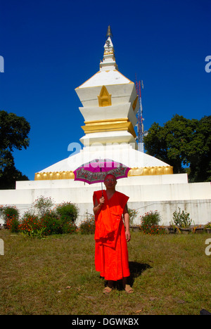 Moine avec un parasol, une robe orange, blanc stupa, Phu Fa, la montagne, Phongsali Laos, Asie du Sud-Est, l'Asie Banque D'Images