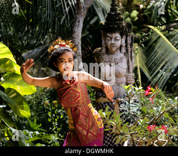 Danseuse balinaise portant un costume traditionnel en face d'une statue de pierre, Candi Dasa, Bali, l'Asie, l'Indonésie Banque D'Images