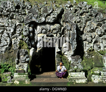 Homme assis balinais à l'entrée de la Goa Gajah ou Elephant Cave, cave temple, Bedulu, Bali, l'Asie, l'Indonésie Banque D'Images