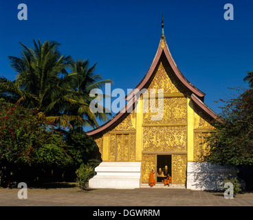 Reliefs d'or, les moines à l'entrée de la maison de transport et Wat Xieng Tong ou TVA Xienthong, Luang Prabang Banque D'Images