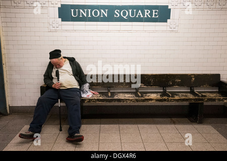 Vieil homme endormi sur un banc de la station de métro Union Square à New York City Banque D'Images