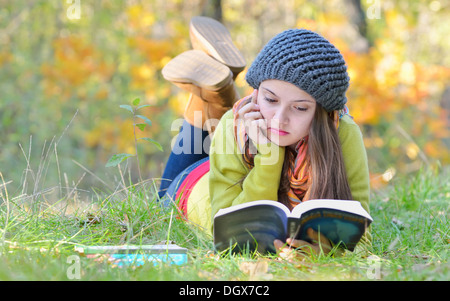 Belle fille lire un livre en plein air du temps d'automne Banque D'Images