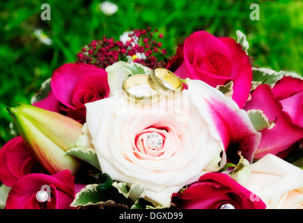 Anneaux de mariage d'or sur un bouquet de roses roses avec Banque D'Images
