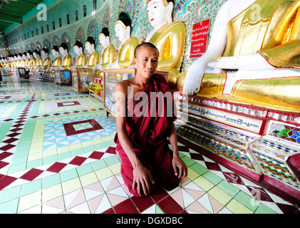 Un moine agenouillé devant les statues de Bouddha dans un monastère, Umin Thounzeh Pagode, Rhône-Alpes, Mandalay, Birmanie, également connu sous le nom de Myanmar Banque D'Images