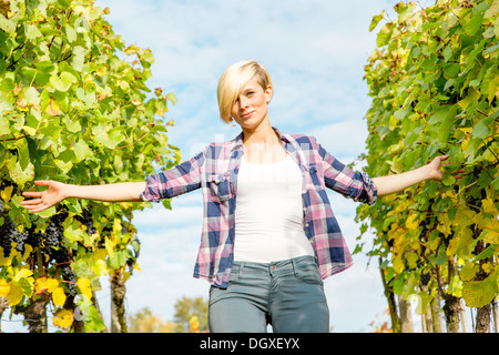 Jeune femme naturelle marche entre la vigne et est en contact avec les feuilles Banque D'Images