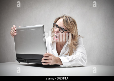 Femme blonde avec des lunettes de crier contre un ordinateur portable Banque D'Images