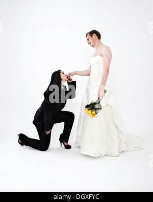 Porter un costume mariée embrassant la main d'un groom portant une robe de mariage, l'échange de vêtements de mariage, Autriche Banque D'Images