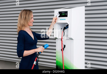 Femme tenant un code carte devant le lecteur d'une accusation CP700d'une station de charge par Siemens, Fürth, Bavière Banque D'Images