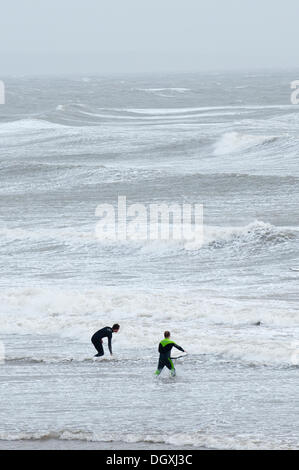 Coney Beach, Porthcawl, UK. 27 octobre 2013. Deux surfeurs de prendre pour les vagues. Le littoral du sud du Pays de Galles est frappé par une forte à force de coup de vent associés à la dépression centrée sur le nord-ouest de l'Irlande que les météorologues prévisions des vents violents d'apporter pour le sud de l'Angleterre et au Pays de Galles dans la nuit de dimanche à lundi et peut provoquer des dégâts similaires à ceux le 15 octobre 1987. Crédit photo : Graham M. Lawrence/Alamy Live News. Banque D'Images