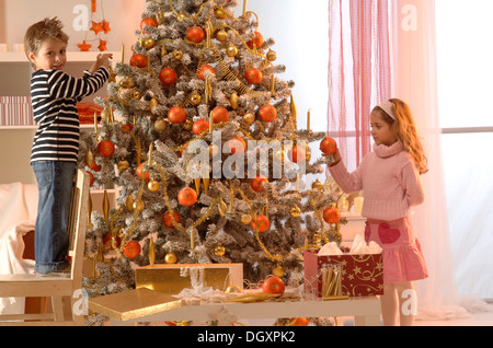 Girl and boy decorating a Christmas Tree Banque D'Images