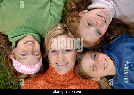 Mère de trois filles allongé dans l'herbe avec leurs têtes ensemble Banque D'Images