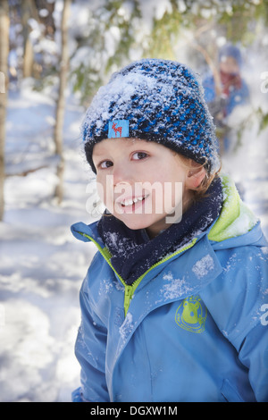 Garçon dans les vêtements d'hiver avec un chapeau couvert de neige Banque D'Images