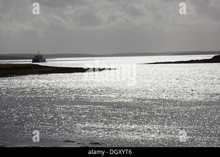 Des îles Orcades, en Écosse. La silhouette pittoresque vue sur un ferry le Houton ferry terminal dans la baie de Houton. Banque D'Images