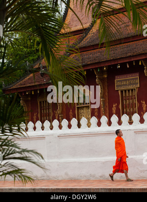 Un moine bouddhiste vêtu en orange promenades au bord de la Wat Sen temple bouddhiste à Luang Prabang, Laos. Banque D'Images