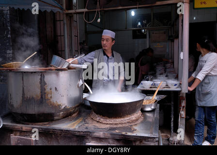 Soupe aux nouilles musulmanes cuisine avec un cuisinier musulman et de grands pots de cuisson sur une poêle de fer dans le quartier musulman de Xian, Shaanxi Banque D'Images