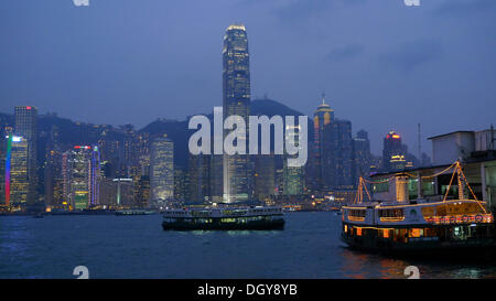 Hong Kong illuminée en soirée avec des gratte-ciel, des immeubles de grande hauteur et le Star Ferry Pier à Hong Kong, Kowloon Central Banque D'Images