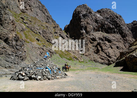 Horseriders voyageant au-delà d'un Ovoo chamaniste, un cairn fabriqués à partir de roches, Yolvn suis Gorge, dans le désert de Gobi Banque D'Images