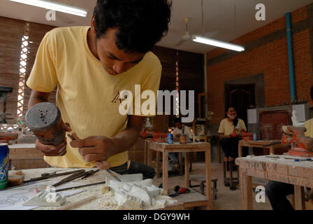 Les jeunes artisans cambodgiens pendant l'artisanat artistique de pierre avec un marteau en bois et d'un burin pour produire un traditionnel Banque D'Images