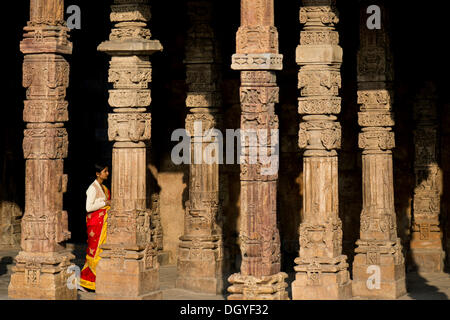 Indian woman walking in entre ornately carved stone piliers, complexe Qutb, Site du patrimoine mondial de l'UNESCO Banque D'Images