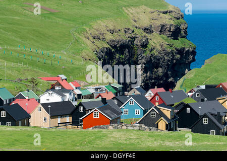 Village typique avec ses maisons colorées, des falaises à l'arrière, mais confortables et disposent, Eysturoy, îles Féroé, Danemark Banque D'Images