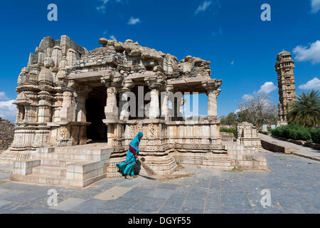 Woman sweeping the dalles de pierre en face de temple ruins, Vijaya Stambha, une victoire tour construite pendant le règne de Rana Kumbha Banque D'Images