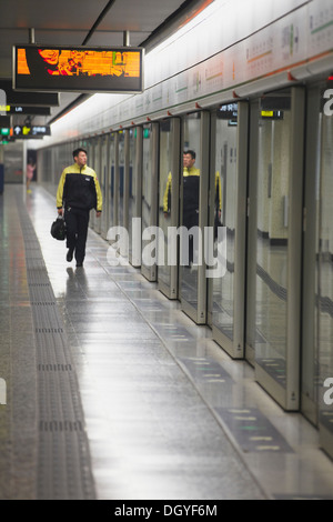 Conducteur de train de marcher le long de la plate-forme de la station de métro Mong Kok, Kowloon, Hong Kong, Chine Banque D'Images