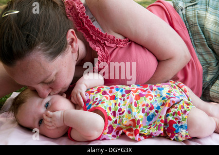 Mère embrassant sa fille de bébé dehors dans le jardin Banque D'Images