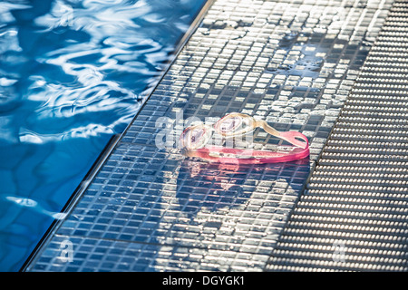 La lumière du soleil qui brille sur une paire de lunettes de natation sur le bord d'une piscine Banque D'Images