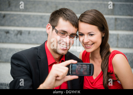 Jeune couple en vêtements d'affaires en plein air - man taking photo with smartphone Banque D'Images