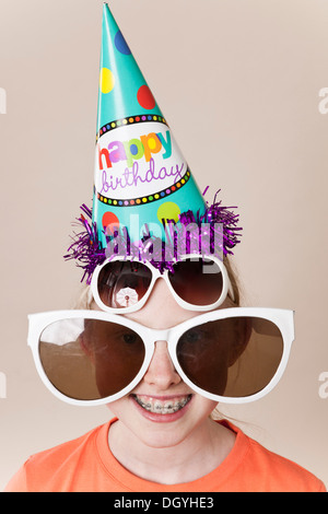 Une jeune fille portant une paire de lunettes de grande nouveauté, une paire de lunettes et d'un party hat Banque D'Images