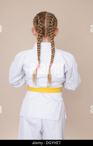 Une jeune fille portant des uniformes d'arts martiaux avec ceinture jaune, vue arrière Banque D'Images