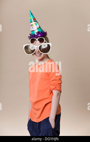Une jeune fille portant une paire de lunettes de grande nouveauté, une paire de lunettes et d'un party hat Banque D'Images