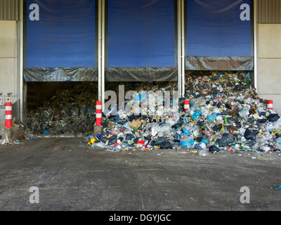 Vidage des déchets ménagers à l'usine de recyclage. À partir de cette zone tampon les machines sont nourris que de trier les matériaux pour le recyclage. Banque D'Images