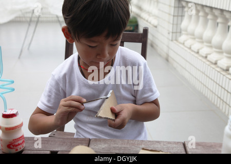 C'est une photo d'un petit garçon asiatique fait whi travail DIY avec du carton pour faire une fusée. Il coupe, colle et peintures. Il est pro Banque D'Images