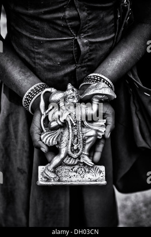 Les pauvres Indiens de basse caste filles mains tenant une statue de Hanuman. L'Andhra Pradesh, Inde. Le noir et blanc Banque D'Images