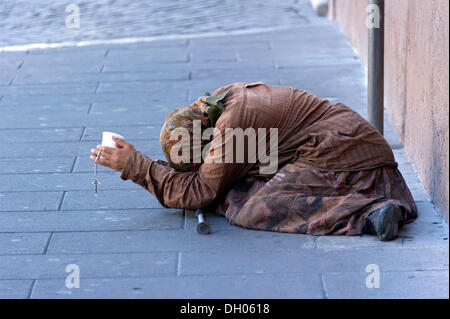 Femme mendiant tenant une tasse en plastique dans une rue de la vieille ville, Rome, Latium, Italie Banque D'Images