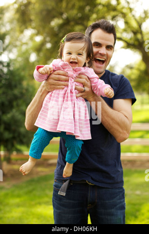 Père holding toddler daughter in park Banque D'Images