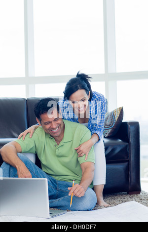 Hispanic couple examining blueprints in living room Banque D'Images