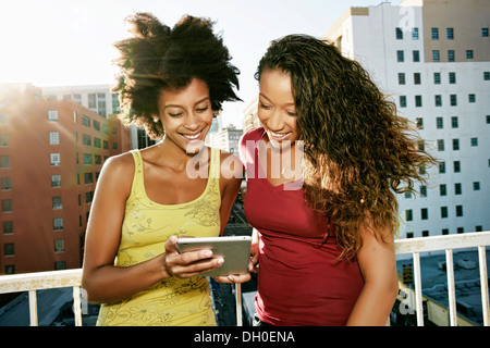 Mixed Race women using digital tablet on urban rooftop Banque D'Images