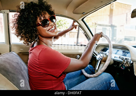 Mixed Race woman driving vintage car Banque D'Images