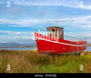 Le comté de Galway, Irlande : bateau de pêche rouge dans les graminées de Bertraghboy Bay près du village de Roundstone Banque D'Images