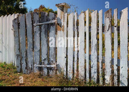 Photographie d'une clôture blanche avec la peinture d'origine et de tomber dans le besoin de réparations. Banque D'Images