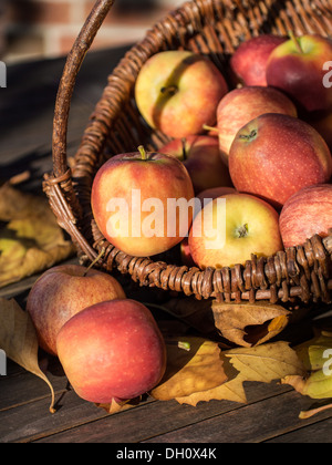 Panier en osier avec des pommes rouges sur une table en bois. Banque D'Images