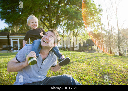 Woman carrying son on shoulders in backyard