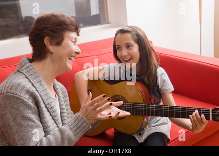 Older Hispanic woman playing music avec sa petite-fille Banque D'Images