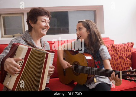 Older Hispanic woman playing music avec sa petite-fille Banque D'Images