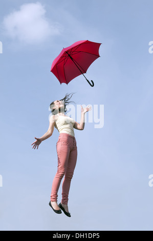 Femme sautant avec parapluie Banque D'Images