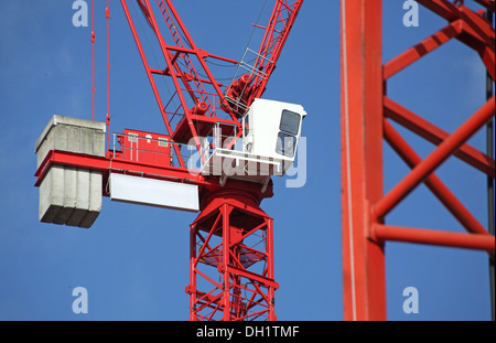 Une grue à tour rouge contre un ciel bleu avec le nom du projet et les logos d'entreprise supprimé Banque D'Images